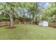 Large fenced backyard with a storage shed and ' play area surrounded by mature trees, providing a private outdoor space at 106 E Delafield Ave, Durham, NC 27704
