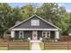 Charming one-story home featuring a pink front door and a cozy front porch, all surrounded by lush greenery and a lovely wood fence at 106 E Delafield Ave, Durham, NC 27704