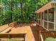 Expansive wood deck with bench seating and screened porch overlooking lush trees at 107 Ashwick Ct, Cary, NC 27513