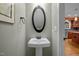 Stylish powder room featuring a pedestal sink with a modern oval mirror and views of the kitchen at 107 Ashwick Ct, Cary, NC 27513