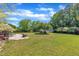 Expansive backyard with lush lawn, outdoor dining set, patio area, and mature trees under a bright, cloudy sky at 107 Stargrass Ave, Clayton, NC 27527