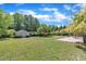 Expansive backyard with lush lawn, storage shed, patio area, and mature trees under a bright, cloudy sky at 107 Stargrass Ave, Clayton, NC 27527