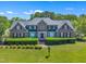 Classic two-story brick home with lush landscaping and mature trees under a bright blue sky at 107 Stargrass Ave, Clayton, NC 27527