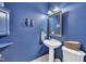 Stylish powder room with blue walls, pedestal sink, decorative mirror and tiled floors at 107 Stargrass Ave, Clayton, NC 27527