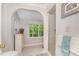 Bright bathroom with arched entry, shower, and large window overlooking the wooded yard at 1104 Berwyn Way, Raleigh, NC 27615
