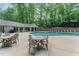 Community swimming pool with lounge chairs and tables surrounded by lush trees at 1104 Berwyn Way, Raleigh, NC 27615