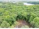 Aerial view of property nestled in a lush, wooded area near a lake at 1115 Trailwood Dr, Raleigh, NC 27606