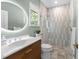 Bright bathroom with a wood vanity, white countertops, round mirror, and glass shower enclosure at 1115 Trailwood Dr, Raleigh, NC 27606