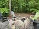Cozy backyard fire pit surrounded by natural stone and Adirondack chairs, perfect for outdoor gatherings at 1115 Trailwood Dr, Raleigh, NC 27606