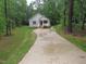 View of a well-maintained property with a long driveway, surrounded by lush greenery and mature trees at 119 Oak Ridge Rd, Franklinton, NC 27525