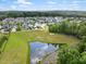 Aerial view of a community with a pond, pool, and lush green landscape at 1205 Quincy Cottage Rd, Hillsborough, NC 27278