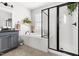 Bright bathroom featuring gray cabinetry, separate tub, and a glass-enclosed shower at 1205 Quincy Cottage Rd, Hillsborough, NC 27278