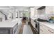 Bright kitchen features white cabinets, quartz countertops, stainless steel appliances, and a view into the dining room at 1205 Quincy Cottage Rd, Hillsborough, NC 27278