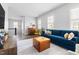 Comfortable living room featuring a blue sofa, ottoman, and neutral rug with wood-look flooring at 1205 Quincy Cottage Rd, Hillsborough, NC 27278