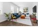 Bright living room with a blue sofa, modern art, and large windows with white shutters at 1205 Quincy Cottage Rd, Hillsborough, NC 27278