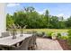 Landscaped outdoor patio features a dining table with seating, planters and a lush green view at 1205 Quincy Cottage Rd, Hillsborough, NC 27278