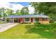 Charming single-story home featuring a red door, brick accents, manicured lawn and a convenient covered carport at 1209 Maple Ave, Apex, NC 27502