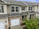 Charming townhome featuring a one-car garage, stone accents, neutral siding and manicured front yard at 1310 Compass Dr, Durham, NC 27713