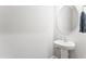 Stylish powder room featuring a pedestal sink, sleek faucet, and a round mirror, complemented by fresh towels at 1310 Compass Dr, Durham, NC 27713