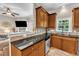 Functional kitchen featuring granite countertops, wooden cabinetry, stainless appliances, and seamless flow to living area at 137 Lanigan Pl, Cary, NC 27513