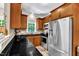 Well-lit kitchen with sleek black countertops, wooden cabinetry, and modern stainless steel appliances at 137 Lanigan Pl, Cary, NC 27513