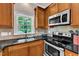 Efficient kitchen with black countertops, wooden cabinets, and a window offering natural light over the sink at 137 Lanigan Pl, Cary, NC 27513