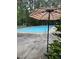 Community pool with lounge chairs and tables under a striped umbrella surrounded by lush greenery and tall trees at 137 Lanigan Pl, Cary, NC 27513