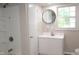 Updated bathroom with white cabinets, a round mirror, and natural light from the window at 1536 Granville Street, Burlington, NC 27215