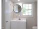 Bathroom with white vanity, a round mirror, and a window providing natural light at 1536 Granville Street, Burlington, NC 27215