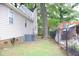 Side yard view of a house with an air conditioning unit near a chainlink fence and large trees at 1536 Granville Street, Burlington, NC 27215