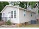 Corner of a tan-sided house with a storm door entry, white trim, and landscaped brick border at 1536 Granville Street, Burlington, NC 27215
