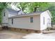 Tan-sided home with a black roof, brick foundation, and a small deck with railings at 1536 Granville Street, Burlington, NC 27215
