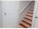 Open staircase with wood tread stairs and white risers, with a white handrail and a white door nearby at 1536 Granville Street, Burlington, NC 27215