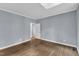 Spacious bedroom featuring hardwood floors, neutral paint, and a view into the hallway through a doorway at 1702 Falls Church Rd, Raleigh, NC 27609
