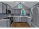 Updated kitchen showcasing stainless steel appliances, gray cabinets, and wood floors at 1702 Falls Church Rd, Raleigh, NC 27609