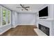 Bright living room with a fireplace, ceiling fan, hardwood floors, and large windows offering natural light at 1702 Falls Church Rd, Raleigh, NC 27609