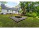 Landscaped backyard featuring a fire pit, green grass and small deck attached to the house at 175 Fox Run Rd, Youngsville, NC 27596