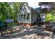 Exterior view of home's rear featuring a sunroom with an abundance of windows, back deck, and lush wooded backyard at 175 Fox Run Rd, Youngsville, NC 27596