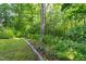 View of a grass filled yard with some landscaping and woods in the background at 175 Fox Run Rd, Youngsville, NC 27596