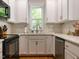 Bright kitchen with white cabinets, tiled backsplash, and stainless steel dishwasher at 201 Cooke St, Raleigh, NC 27601