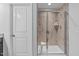 Tiled shower stall with glass door, shower seat, and white door at 210 Mayfield Dr, Apex, NC 27539