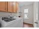 This laundry room has a front load washer and dryer with wood floor, a window, and cabinet storage at 210 Mayfield Dr, Apex, NC 27539