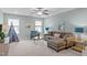 Well lit living room with two large windows, a ceiling fan, plush furniture, and neutral colored walls at 210 Mayfield Dr, Apex, NC 27539