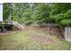 Large backyard with a deck featuring stairs leading down to a spacious lawn and bordered by a wooden fence and mature trees at 2216 Lawrence Dr, Raleigh, NC 27603