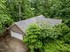 An aerial view of the brick home featuring an attached garage and surrounded by lush trees at 224 Crawford Rd, Hillsborough, NC 27278