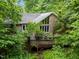 Charming brick home featuring a spacious deck surrounded by lush green trees and landscaping at 224 Crawford Rd, Hillsborough, NC 27278