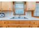 Close up of a stainless steel kitchen sink with wood cabinets and view from the window at 2619 Steel Bridge Rd, Sanford, NC 27330