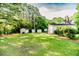 View of backyard with storage sheds and outbuildings surrounded by a well-maintained lawn and mature trees at 2619 Steel Bridge Rd, Sanford, NC 27330