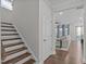 Hallway with wood stairs leading to a living room with a sofa and many windows at 2924 Watering Hole Way, Apex, NC 27502