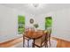 Sunlit dining room with hardwood floors, a wooden table, and windows overlooking the yard at 3405 Bonaparte Way, Durham, NC 27707